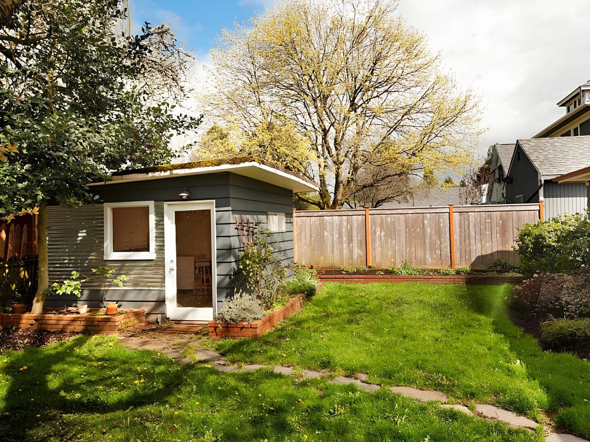 Small gray shed with white framed windows